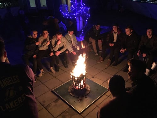 Schüler der Berufsfachschule Nürnberg sitzen um ein Lagerfeuer herum
